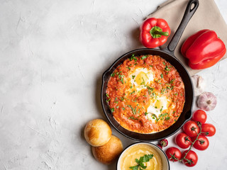 Shakshuka with bell pepper, tomatoes, hummus and rolls. Top view, place for text.
