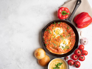 Shakshuka with bell pepper, tomatoes, hummus and rolls. Top view, place for text.