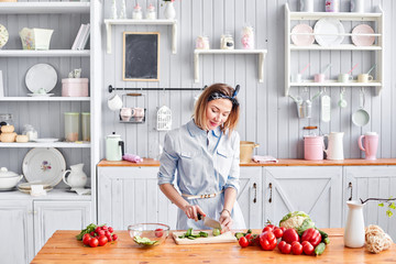 Beautiful young woman is preparing vegetable salad in the kitchen. Healthy Food. Cooking at home. Dieting Concept.