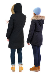 Back view of couple couple in winter jackets pointing.