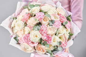 Persian buttercup in womans hands. Bunch pale pink ranunculus flowers with green eucalyptus. The work of the florist at a flower shop