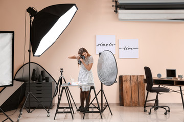 Young woman taking picture of macarons and milk in professional studio