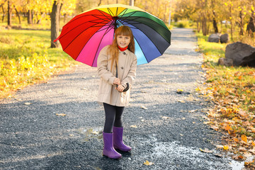 Cute little girl with umbrella in autumn park