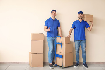 Delivery men with boxes near color wall