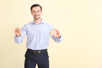 Male real estate agent with key on light background