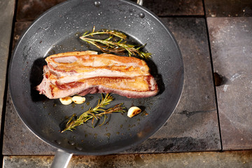 fried ribs of lamb. Cooking with fire in frying pan. Professional chef in a kitchen of restaurant cooking. Man frying food in flaming pan on hob.