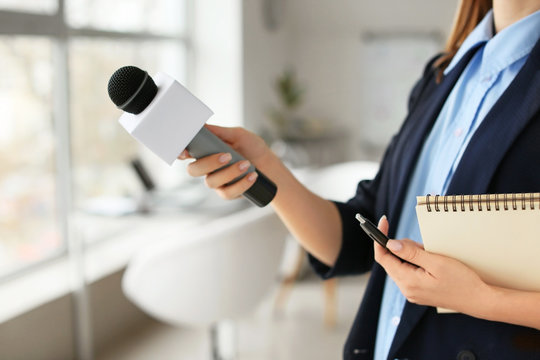 Female journalist with microphone having an interview in office