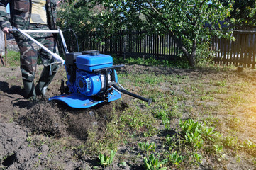 plowing the land in the garden with a cultivator. a man plows the land with the help of motor cultivator.