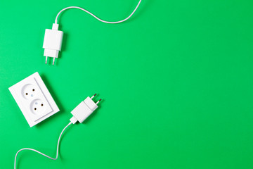 Fototapeta premium White electrical power sockets and power plug on light green background. Top view