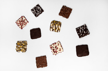 Many beautiful multi-colored cookies in chocolate on a white background