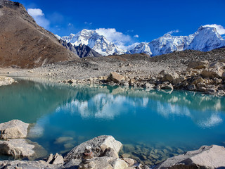Ngozumpa Tsho, the fifth Gokyo lake., hills and snow-capped mountains. Beautiful reflection in the water. Sunny day and marvellous blue sky. Gokyo lakes and Cho Oyu base camp trek, Solokhumbu, Nepal.