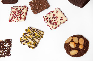 Many beautiful multi-colored cookies in chocolate on a white background