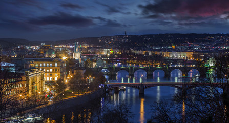 Prague, Czech Republic - Panoramic skyline of the city of Prague at night with purple clouds. Included the illuminated famous Charles Bridge, St. Francis Of Assisi Church and River Vltava at winter