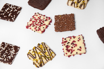 Many beautiful multi-colored cookies in chocolate on a white background