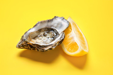 Tasty oyster with lemon on color background