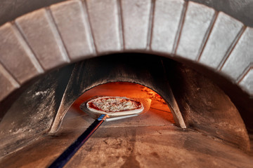 Baked tasty margherita pizza in Traditional wood oven in Naples restaurant, Italy. Original neapolitan pizza. Red hot coal.