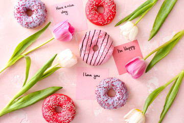 Composition with sweet donuts and flowers on color background