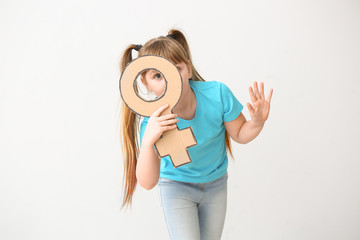 Fototapeta premium Little girl with symbol of woman on light background. Concept of feminism