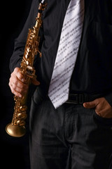Naklejka premium soprano saxophone in the hands of a guy on a black background