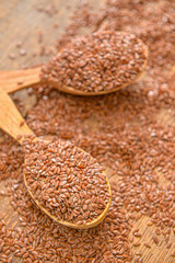 Spoons with flax seeds on wooden background
