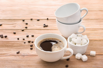 Cup of hot coffee and sugar on table