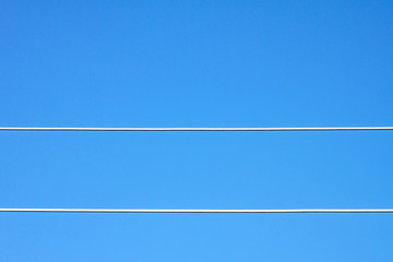 Two white wires stretch at the bottom of the frame amid blue clear sky