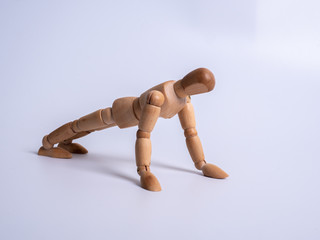 Small wooden dummy during push ups on white background