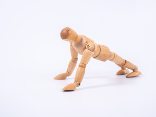 Small wooden dummy during push ups on white background