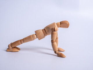Small wooden dummy during push ups on white background