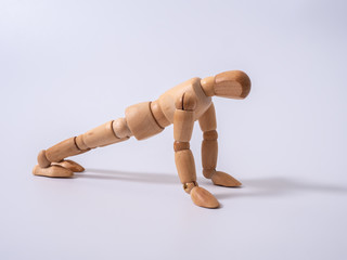 Small wooden dummy during push ups on white background