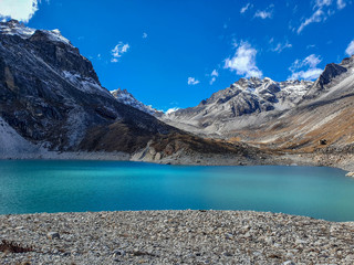 Obraz premium Ngozumpa Tsho, the fifth Gokyo lake., hills and snow-capped mountains. Beautiful reflection in the water. Sunny day and marvellous blue sky. Gokyo lakes and Cho Oyu base camp trek, Solokhumbu, Nepal.