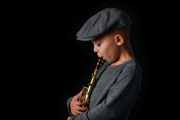 Naklejka premium happy child plays saxophone in studio