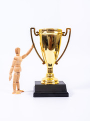 Wooden toy figure and golden trophy cup on white background