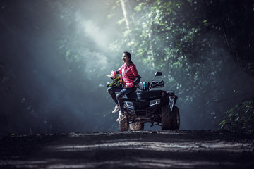 Elegant woman riding quadricycles ATV in forest