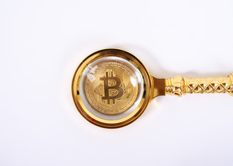 Golden bitcoin magnifying glass on a blurred background of coins