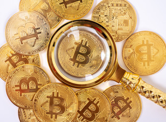 Golden bitcoin magnifying glass on a blurred background of coins