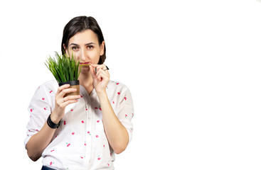The girl in a white blouse holds a houseplant. Young woman on a white background with a small pot of office plant. copy space, isolated