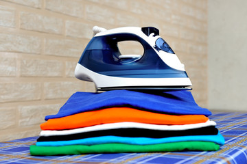 Electric steam iron and a stack of ironed t-shirts