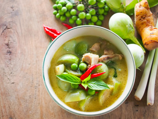 Chicken green curry with coconut and Thai food cooking  ingredients on wooden table.