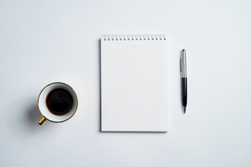 white office Desk top view with Notepad, pen and coffee Cup, minimalistic design, top view,copy space,flat lay