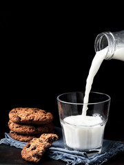 Fresh milk or yogurt is poured into a glass. A glass on a blue stand is located on a dark metal...