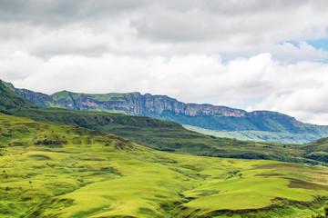 Fototapeta premium View to steep rocky mountains, with green and soft meadows in the foreground, Maloti Drakensberg Park, South Africa