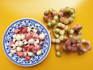 Peeled Manila Tamarind or makham thet in Thailand onto a beautiful patterned dish with many green...