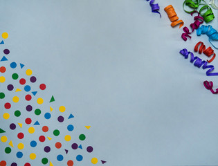 The concept of birthday. Border of colored paper streamers and confetti on a gray background. Free space.