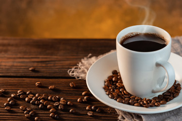 White coffee cup and coffee beans on wooden background