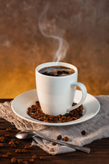 White coffee cup and coffee beans on wooden background