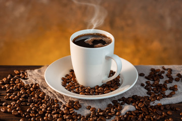 White coffee cup and coffee beans on wooden background