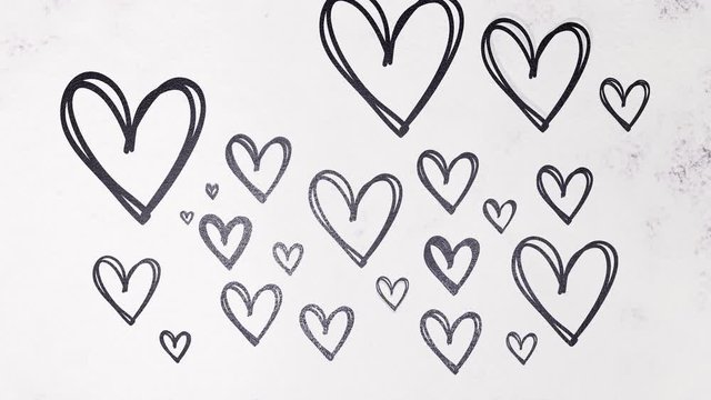 Valentine's Day. Background from flour with appearing hearts of black color. Stop motion.