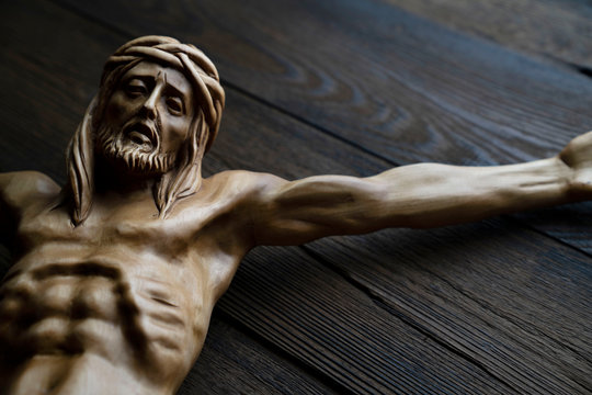  Cruciefied Jesus figure isolated on rustic dark brown table.