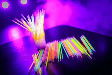 Multicolored UV fluorescent sticks in a glass at a techno party